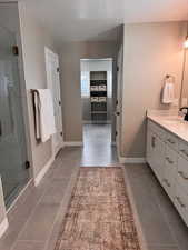 Full bathroom with a shower stall, vanity, a textured ceiling, a spacious closet, and light tile patterned floors