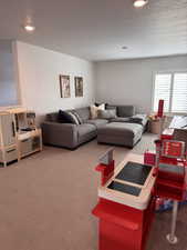 Living room with dark carpet, a textured ceiling, and recessed lighting