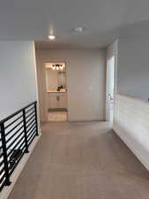 Corridor featuring light carpet and baseboards