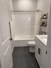 Full bath with vanity, shower / bath combination with curtain, and dark tile patterned flooring