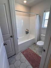 Bathroom featuring shower / tub combo with curtain and light tile patterned flooring