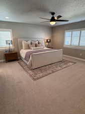 Bedroom with multiple windows, a textured ceiling, carpet flooring, and ceiling fan