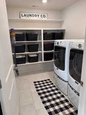Laundry room with separate washer and dryer, light tile patterned floors, and recessed lighting