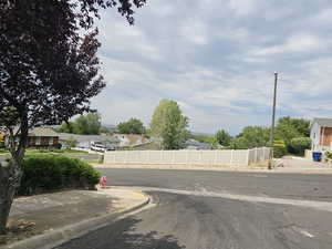 View of asphalt street with a residential view, curbs, street lights, and sidewalks