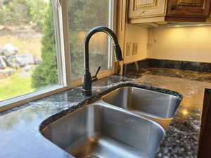 Kitchen view of dark stone counters and a sink