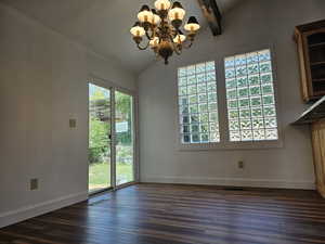 Unfurnished dining area with hanging lights, dark wood-style flooring, and vaulted ceiling with beams