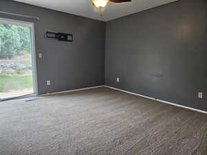 Carpeted spare room with baseboards and a ceiling fan