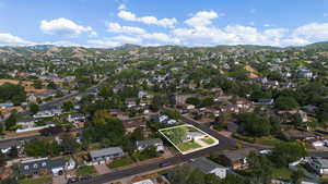 View of property location with property parcel outlined, a mountainous background, and nearby suburban area