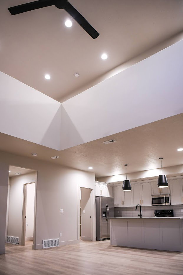 Kitchen with stainless steel appliances, open floor plan, hanging light fixtures, light wood finished floors, and a kitchen island with sink