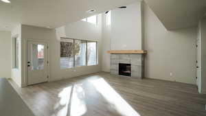 Unfurnished living room with a fireplace, light wood finished floors, and a high ceiling