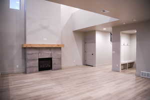 Unfurnished living room with a tile fireplace, light wood finished floors, and recessed lighting