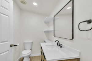 Half bathroom with vanity, light wood-style floors, and recessed lighting