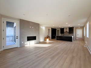 Unfurnished living room with light wood-type flooring, a fireplace, and recessed lighting