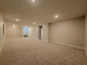 Finished below grade area with recessed lighting, light colored carpet, and a textured ceiling
