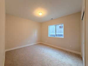 Unfurnished bedroom featuring a textured ceiling, a closet, and light carpet