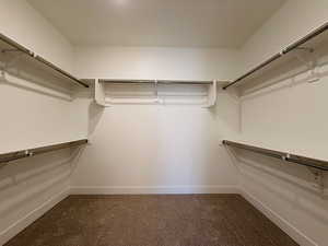 Walk in closet featuring dark carpet