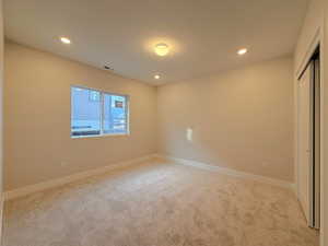 Unfurnished bedroom with recessed lighting, light carpet, and a closet