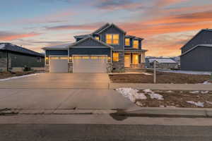 Craftsman house with stone siding, a garage, concrete driveway, board and batten siding, and a porch