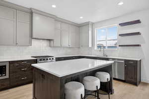 Kitchen with light stone countertops, a breakfast bar, stainless steel appliances, a center island, and open shelves
