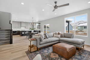 Living area featuring a mountain view, a ceiling fan, a chandelier, and light wood-style floors