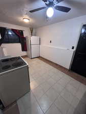 Kitchen featuring electric range oven, freestanding refrigerator, a textured ceiling, light tile patterned floors, and ceiling fan