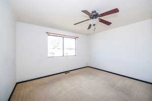 Spare room featuring light colored carpet and a ceiling fan