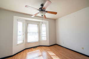 Empty room with a textured ceiling, a ceiling fan, and light wood finished floors