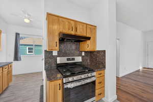 Kitchen with gas range, dark countertops, tasteful backsplash, and ceiling fan