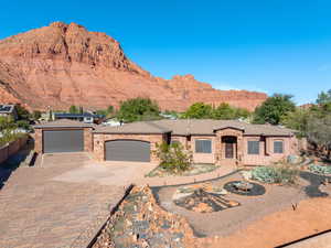 View of front of house featuring decorative driveway, stone siding, a mountain view, and a garage