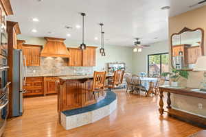 Kitchen featuring wood finish cabinetry, light stone countertops, a kitchen breakfast bar, and stainless steel appliances
