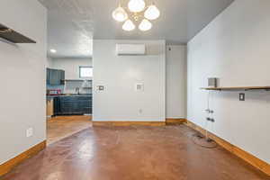 Unfurnished dining area featuring concrete floors, hanging lights, and a textured ceiling