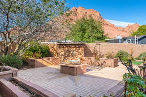 Fenced backyard featuring a fire pit, a patio, and a mountain view
