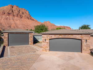 View of front of home featuring stone siding, a mountain view, a garage, and driveway