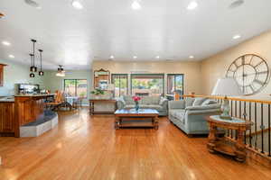 Living area with light wood-style flooring, a ceiling fan, and recessed lighting