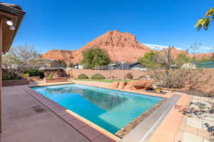 View of pool featuring patio surround, a mountain view, and a fenced backyard