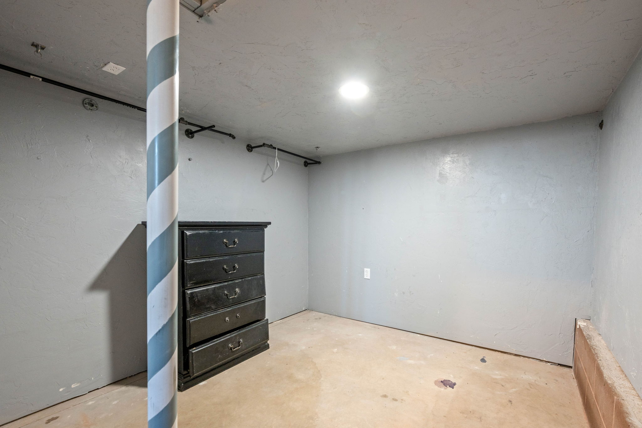 Unfurnished bedroom with concrete flooring and a textured wall