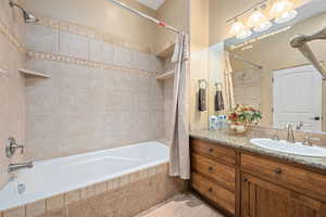 Bathroom featuring tiled shower / bath, vanity, and light tile patterned floors