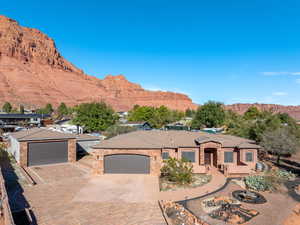 View of front facade featuring decorative driveway, a mountain view, a garage, and stone siding