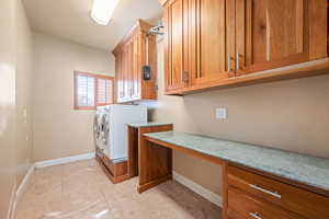 Laundry area with washing machine and clothes dryer, light tile patterned floors, and cabinet space