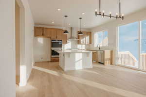 Kitchen featuring stainless steel appliances, light wood-style floors, a center island, a breakfast bar, and light wood finish cabinetry