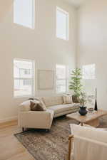 Living area featuring plenty of natural light, light wood-style floors, and a high ceiling