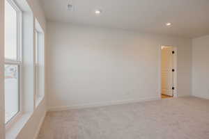 Unfurnished room with light carpet, plenty of natural light, and recessed lighting