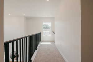 Hall with carpet flooring, recessed lighting, and an upstairs landing