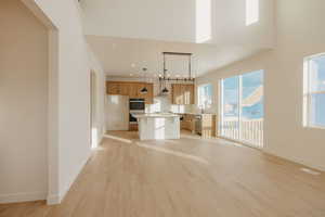 Kitchen with light countertops, a center island, light wood-style flooring, open floor plan, and stainless steel appliances