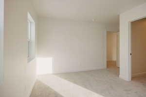 Unfurnished room featuring light carpet and baseboards