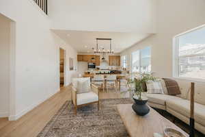 Living room featuring light wood-style floors, a high ceiling, and hanging lights