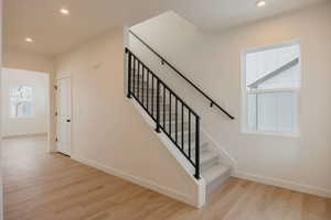 Stairs featuring wood finished floors and recessed lighting
