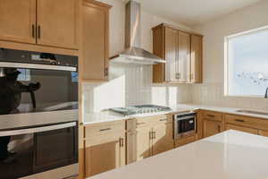 Kitchen with stainless steel appliances, light stone countertops, and backsplash