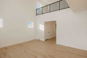 Empty room with light wood-style flooring and a high ceiling
