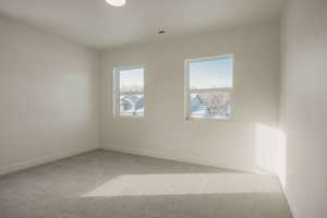Empty room with light colored carpet and baseboards